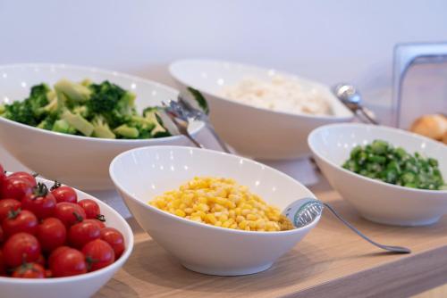 a table topped with bowls of different types of vegetables at Just Inn Premium Toyohashi Station in Toyohashi