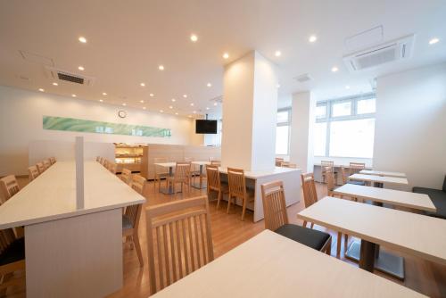 a restaurant with tables and chairs in a room at Just Inn Premium Toyohashi Station in Toyohashi