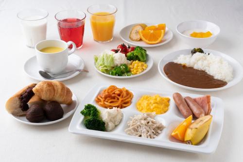 a table with plates of food and cups of coffee at Just Inn Premium Toyohashi Station in Toyohashi