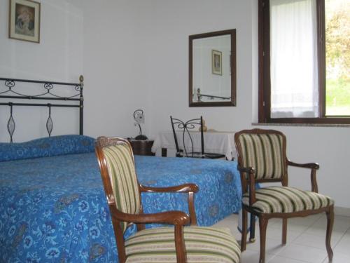 a bedroom with a bed and two chairs and a mirror at Il Giardino di Valentina in Escolca