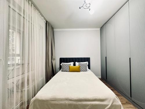 a bedroom with a large bed with a yellow pillow at Ala Park apartment in Almaty