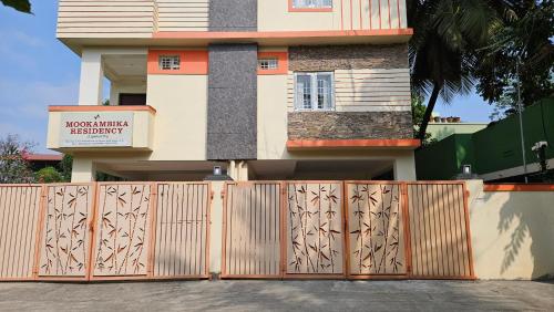 a house with a wooden gate in front of it at Mookambika Serviced Apartment in Coimbatore