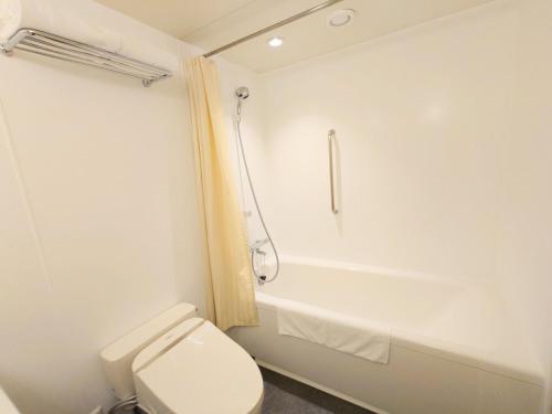 a white bathroom with a toilet and a bath tub at Narita Tobu Hotel Airport in Narita