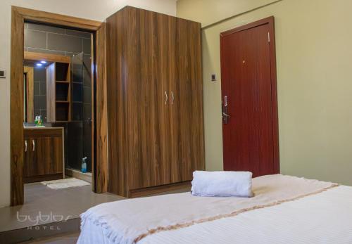 a bedroom with a bed and wooden cabinets at Byblos Hotel-Sky Osu in Accra