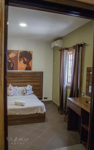 a bedroom with a bed and a sink and a mirror at Byblos Hotel-Sky Osu in Accra