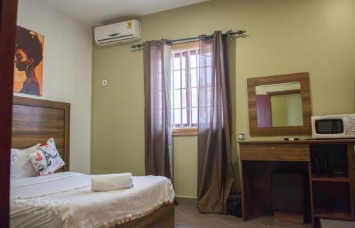 a bedroom with a bed and a mirror and a window at Byblos Hotel-Sky Osu in Accra