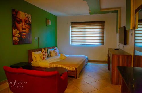 a bedroom with a bed and a couch and a tv at Byblos Hotel-Sky Osu in Accra