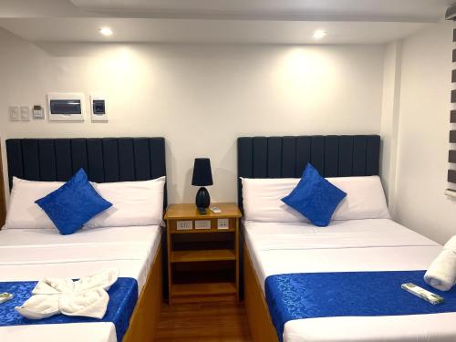 two beds with blue pillows in a room at FountainBlue Hotel and Banquet Hall in Daraga