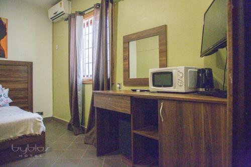 a room with a desk with a microwave and a mirror at Byblos Hotel-Sky Osu in Accra
