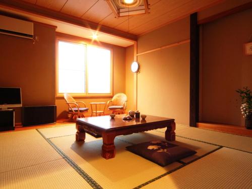 a living room with a wooden coffee table in a room at Hatoguruma Kawabata in Nozawa Onsen