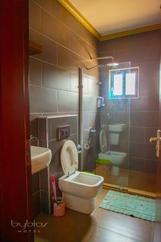 a bathroom with a toilet and a sink and a shower at Byblos Hotel-Sky Osu in Accra