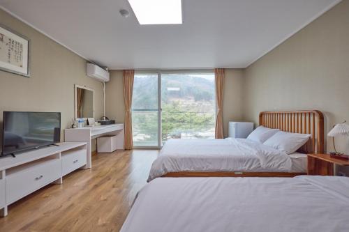 a bedroom with two beds and a flat screen tv at Manhae Maeul in Inje