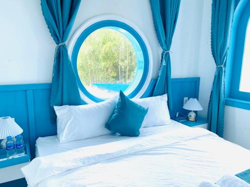 a blue bedroom with a bed with a round window at Robinson Homestay - Cù Lao Mái Nhà in Tuy An