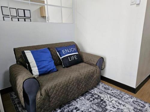 a couch with two pillows on it in a room at The Celandine Balintawak "Ahh-Mazing Suite" Quezon City in Quezon City