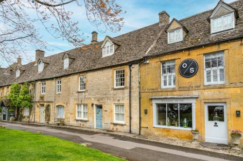 an old brick building with a clock on it at Arch Row Cottage - Stow on the Wold in Stow on the Wold