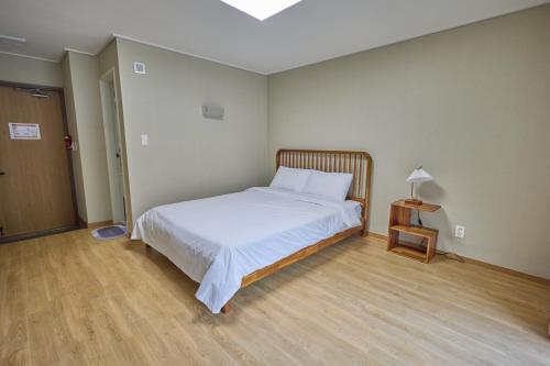 a bedroom with a bed and a lamp on a wooden floor at Manhae Maeul in Inje