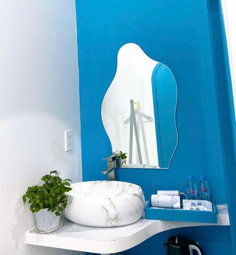 a blue bathroom with a white tub and a mirror at Robinson Homestay - Cù Lao Mái Nhà in Tuy An