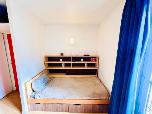 - une petite chambre avec un lit et un rideau bleu dans l'établissement Chic Studio in Central Paris, à Paris