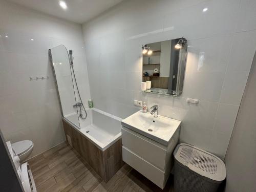 a bathroom with a sink and a tub and a toilet at Apartament Kasprzaka in Bydgoszcz