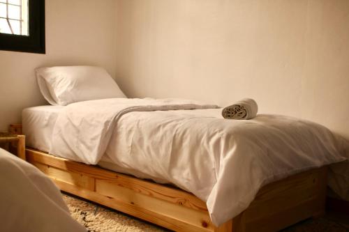 a bed with white sheets on it in a room at Azurf - Imsouane Surf House in Imsouane