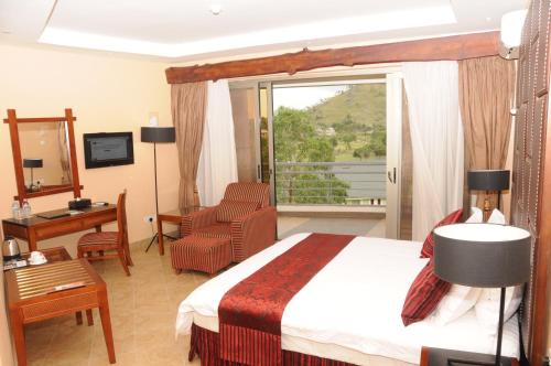 a hotel room with a bed and a desk and a window at Igongo Country Hotel & Cultural Centre in Kyabinunga