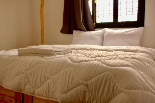 a white bed with white sheets and pillows at Azurf - Imsouane Surf House in Imsouane