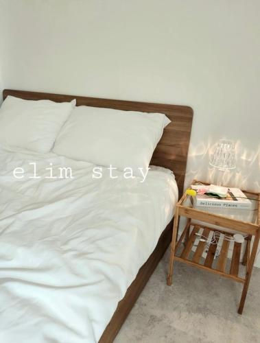 a bed with white sheets and a side table at Elimhouse in Ansan