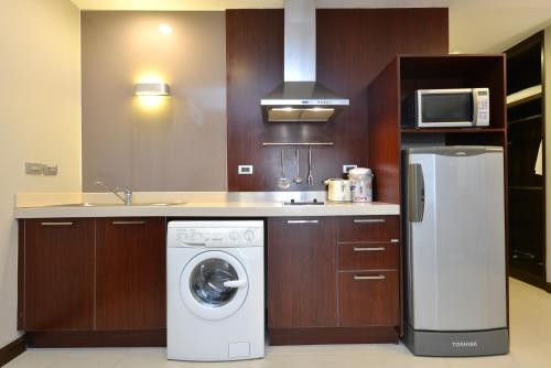 a kitchen with a washing machine and a microwave at Grand Asoke Suites Boutique Residence in Bangkok