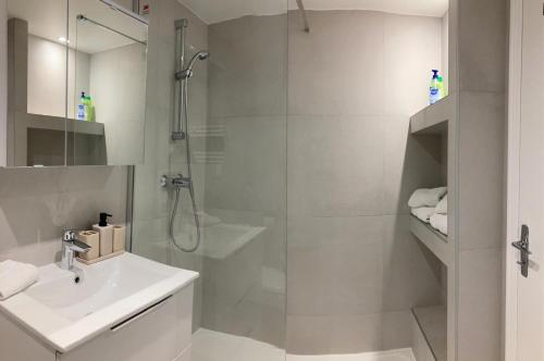 une salle de bain blanche avec une douche et un lavabo dans l'établissement Grand studio hyper centre avec balcon TOUT REFAIT MARS 2025, à Deauville