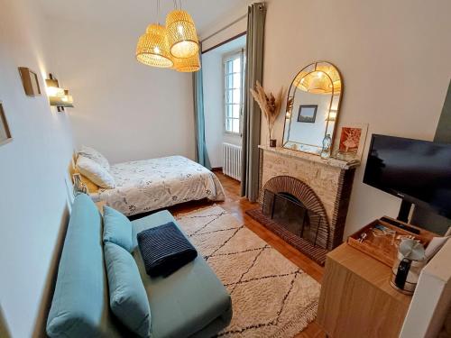 Una sala de estar con un sofá y una chimenea. en La Fontaine du Mas, en Thiviers