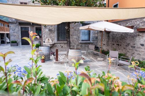 a patio with an umbrella and chairs and tables at Corte Giorgi in Breno