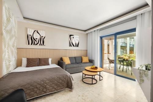 a bedroom with a bed and a couch and a table at Royal Park Apartments Resort by Sea N Rent in Eilat