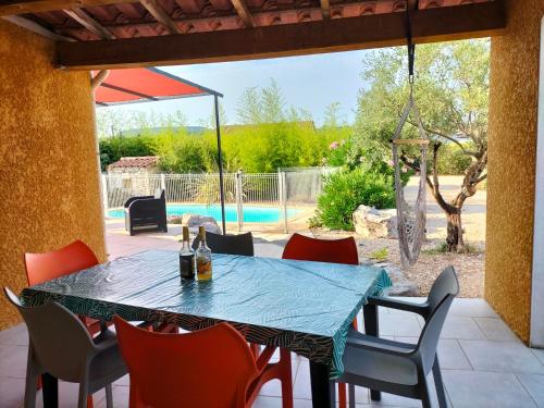 un patio avec une table et des chaises et une piscine dans l'établissement Gîte soleil ardéchois Manon, à Sampzon