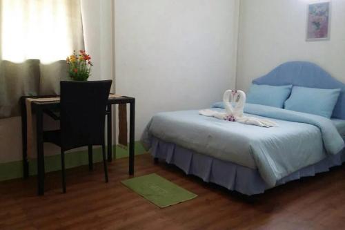 a bedroom with a bed and a table and a chair at Coconut Home Resort in Damnoen Saduak