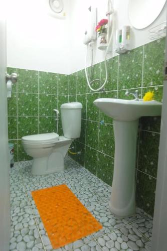 a green tiled bathroom with a toilet and a sink at Coconut Home Resort in Damnoen Saduak