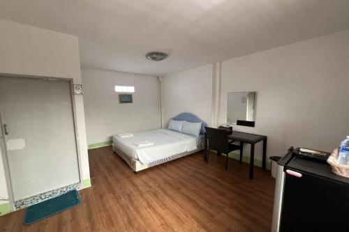 a small room with a bed and a desk at Coconut Home Resort in Damnoen Saduak