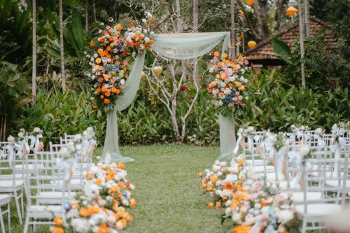 an aisle with white chairs and orange flowers at La Siesta Hoi An Resort & Spa in Hoi An