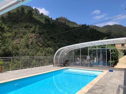 une maison avec une piscine en face d'une montagne dans l'établissement Le Massoulier Pergola, à LʼEstréchure
