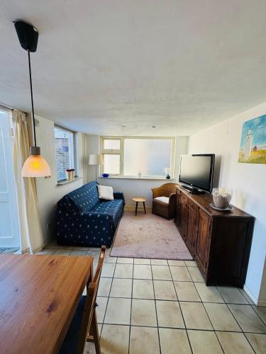 a living room with a couch and a tv at Strandhuisje Quarles in Noordwijk