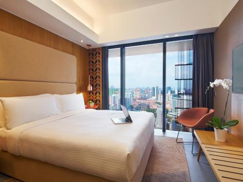 a hotel room with a bed and a desk with a laptop at Oasia Hotel Downtown, Singapore by Far East Hospitality in Singapore