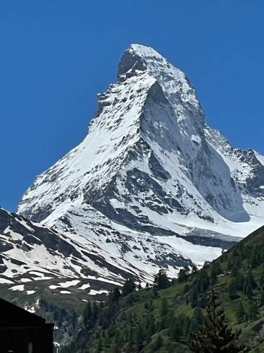 a large snow covered mountain with a blue sky at Studio Chalet with terrace & Matterhorn view in Zermatt