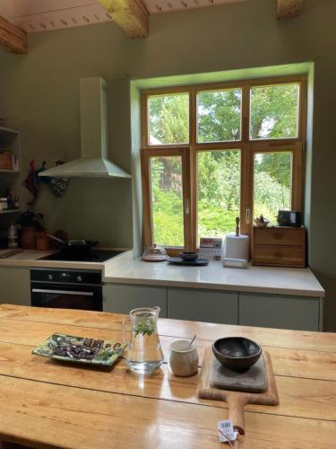 a kitchen with a wooden table and a window at Ielejas A place for cool living in Vircava