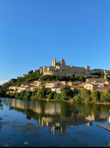 un château au sommet d'une colline à côté d'une rivière dans l'établissement Foch 3-Studio-Beziers center -wifi -tv connected, à Béziers