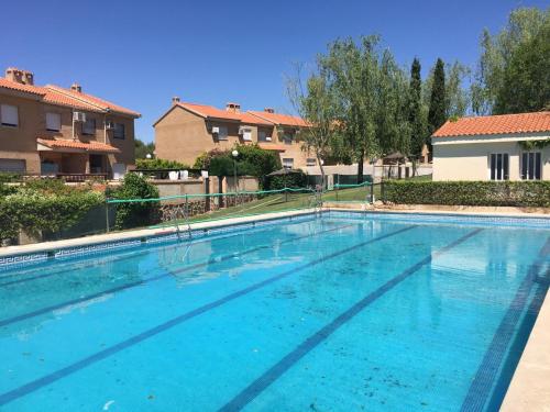 a large blue swimming pool with buildings in the background at Habitación en Chalet con Piscina in Argés