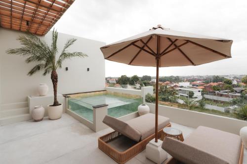 a balcony with a swimming pool and an umbrella at Sore Escape Tumbak Bayuh by Betterplace in Tumbak Bayuh
