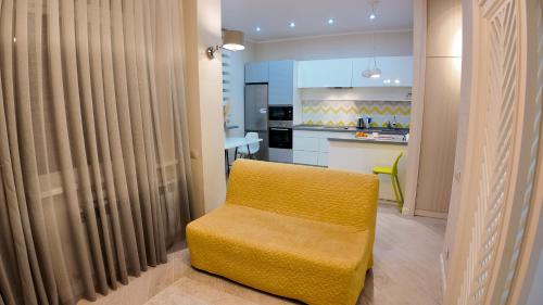 a yellow chair in a room with a kitchen at Apartments on EXPO, Mega SilkWay in Astana