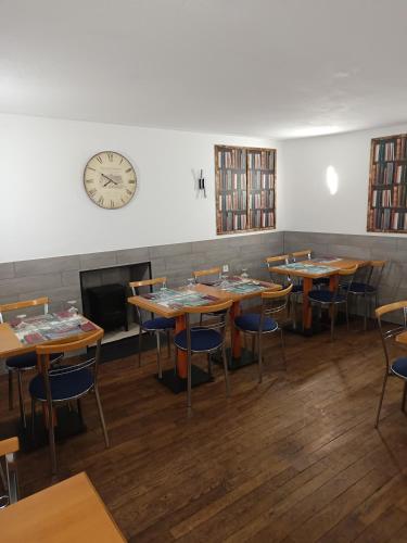 une pièce avec des tables et des chaises et une horloge au mur dans l'établissement Hotel du Centre, à Châlus