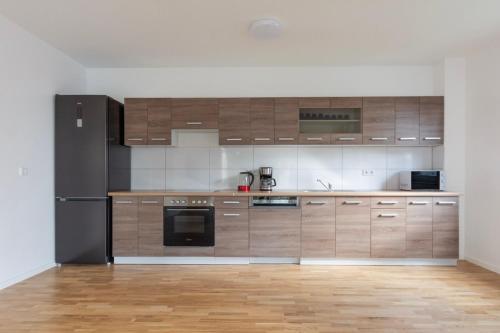 a kitchen with wooden cabinets and a black refrigerator at T&K Apartments - BERGISCH GLADBACH - 7 Comfortable Apartments - 20 min to Fair Messe Cologne in Cologne