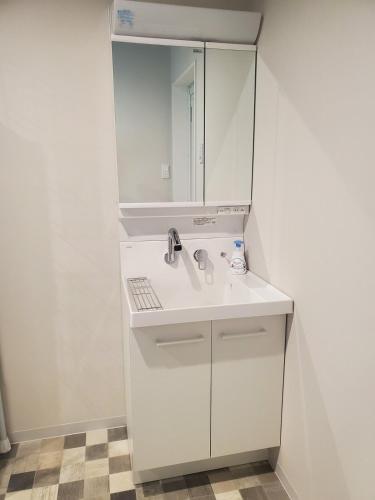 a white bathroom with a sink and a mirror at 古都ひかり3 in Takayama