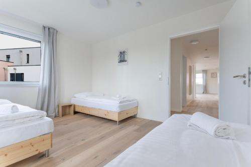 a white bedroom with two beds and a window at T&K Apartments - BERGISCH GLADBACH - 7 Comfortable Apartments - 20 min to Fair Messe Cologne in Cologne
